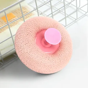 Nahaufnahme des rosa Peeling-Badeschwamms mit Saugnapf-Griff im sauberen Badezimmer-Setup.
