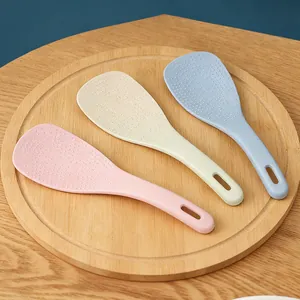 Gros plan de cuillères à riz en paille de blé rose, beige et bleu avec texture antiadhésive.