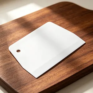 White plastic dough scraper bench scraper baking tool with hanging hole for kitchen use.
