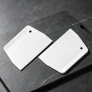 White plastic bench scraper, trapezoidal dough cutter tool with hanging hole for baking.