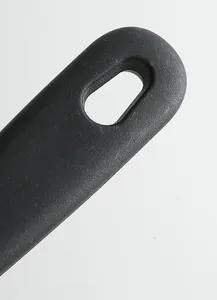 Détail de la poignée en plastique noir du racloir de cuisine avec trou, outil robuste
