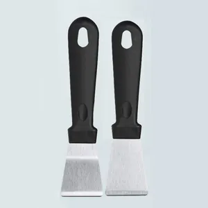 Outil de grattoir de nettoyage de cuisine en acier inoxydable avec poignee ergonomique noire.