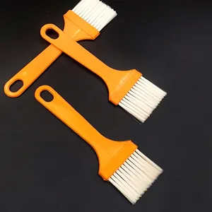 Reinigungsbürste mit orangenem Griff und weissen Borsten fuer Kueche und Grill im Detail.