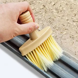 Detail shot of soft bristle cleaning brush clearing dust from tight window tracks and gaps.