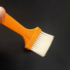 Multifunktionale Reinigungsbürste mit orangenem Plastikgriff und weißen Borsten für den Alltag.