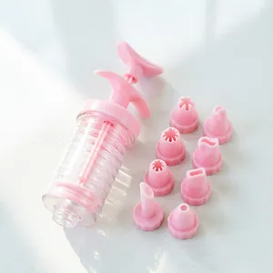 Pink plastic cookie press gun and 8 piping nozzles set, detail view of baking tool.