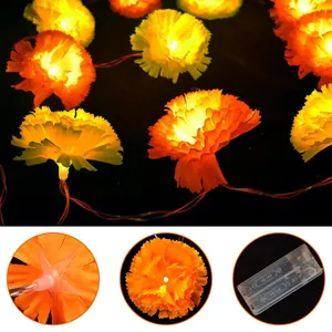 Detailed view showing marigold petal texture and battery compartment of LED string lights
