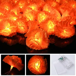 Detailed close-up of orange marigold LED flower string lights and the battery pack