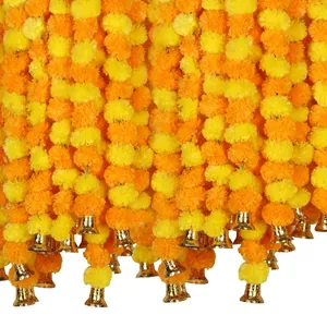 Detail view of artificial orange and yellow marigold garlands with decorative gold bells