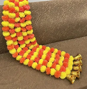 Detail view of artificial marigold garland with gold bells for festive decoration
