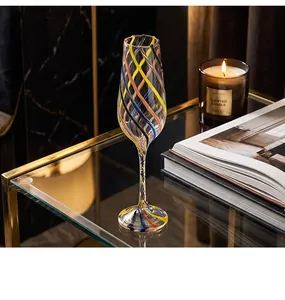 Hand-blown colorful spiral thread champagne flute glass on a glass table with candle