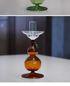 Detail of pear-shaped amber glass candlestick holder with clear cup and green leaf
