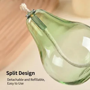 Close-up of green pear-shaped glass oil lamp with cotton wick and split design