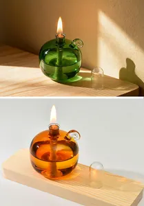 Detail view of green and amber spherical glass oil lamps lit on a wooden surface.