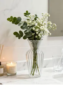 Dettaglio di un vaso di vetro scanalato con fiori freschi su marmo