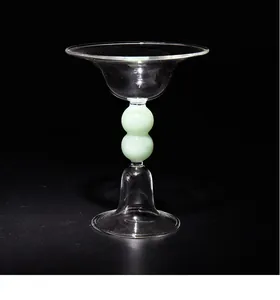 Dettaglio ravvicinato di un elegante portacandele in vetro con stelo a sfere verdi