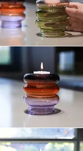 Primer plano de un portavelas retro de vidrio de colores en forma de aro con vela.