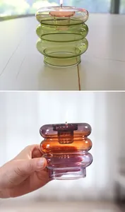 Primer plano de un portavelas de cristal de colores con anillos apilados y una vela