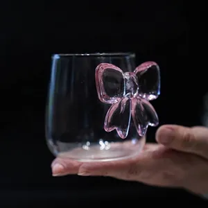 Eleganter Glasbecher mit kreativem rosa 3D-Schleifengriff für stilvolle Tische.