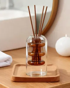 Close-up of modern double-layer amber glass reed diffuser bottle on a wooden tray