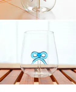 Close-up detail of a minimalist transparent glass cup featuring a blue glass bow design