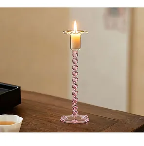 Close-up detail of a vintage pink spiral glass candle holder on a rustic wooden table