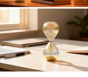 Iridescent glass hourglass timer with sparkling glitter on white desk detail view