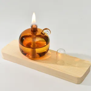 Modern amber spherical glass oil lamp on natural wooden stand with a lit flame