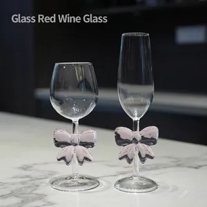 Elegant glass wine glasses with decorative pink glass bows on the stems for romantic occasions.