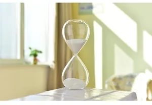 Makrodetail eines hochwertigen transparenten Sandglases mit feinem weißem Sand gefüllt.