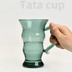 Elegant green wavy borosilicate glass mug for coffee or tea in a hand-held view
