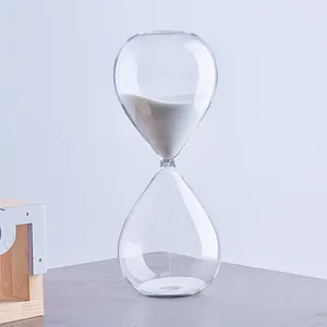 Elegante clessidra minimalista in vetro trasparente con sabbia bianca su fondo grigio