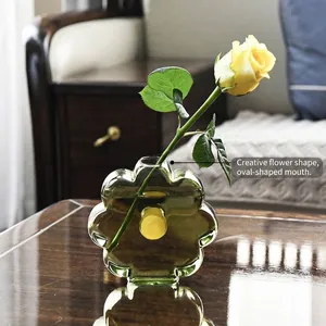 Minimalist green flower-shaped glass vase for hydroponic plants on a wooden table