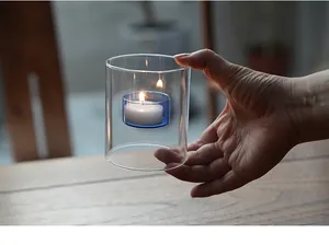 Dettaglio di un portacandele in vetro antivento con una coppa interna blu per cene romantiche