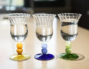 Primer plano de tres copas francesas vintage con tallos de cuentas de colores en mesa