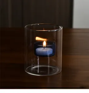 Primer plano de una vela de té encendida en un elegante portavelas de vidrio doble