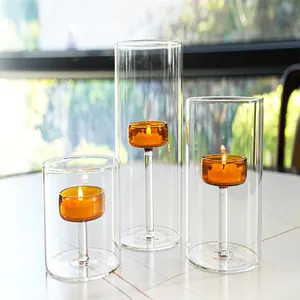 Close-up of three amber glass candle holders with lit tea lights on a table
