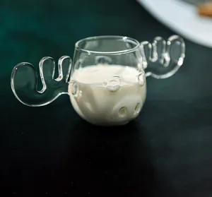 Detailansicht eines elchförmigen Glasbechers mit Milch auf dunklem Hintergrund