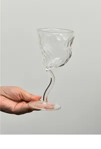 Primo piano di un calice da vino con gambo ritorto e trama ghiacciaio tenuto in mano