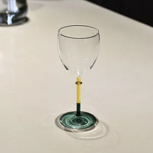 Elegant color-blocked wine glass featuring an amber and green stem on stone surface