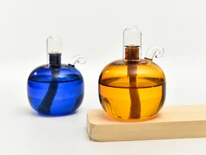 Nahaufnahme kugelförmiger Glasöllampen in Blau und Bernstein auf Holzsockel.