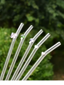 Close-up of reusable bent glass straws with cute butterfly and mushroom charms