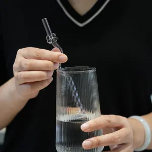 Reusable clear glass drinking straw with cute butterfly ornament in a tall ribbed glass