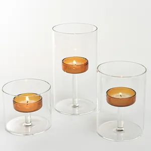 Set of three cylindrical glass candle holders with amber interior cups for tea lights.