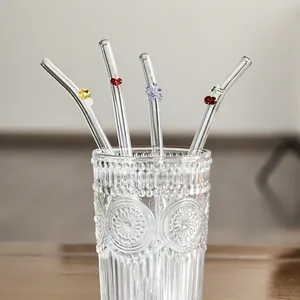 Reusable heat-resistant glass straws with cute butterfly and heart charms in a glass