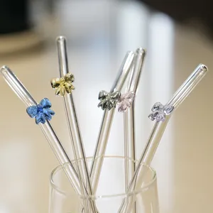 Colorful glass straws featuring cute bow decorations in a transparent glass cup