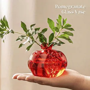 Red pomegranate shaped glass vase held in hand for mini home table decor