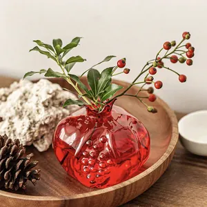Elegant red pomegranate-shaped glass vase displayed on a wooden tray for home table decor