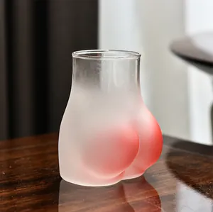 Nahaufnahme einer kreativen pinkfarbenen Glastasse in Gesäßform auf einem Holztisch
