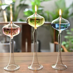 Detailed close-up of three elegant lit glass oil lamps with pink, yellow and blue oil